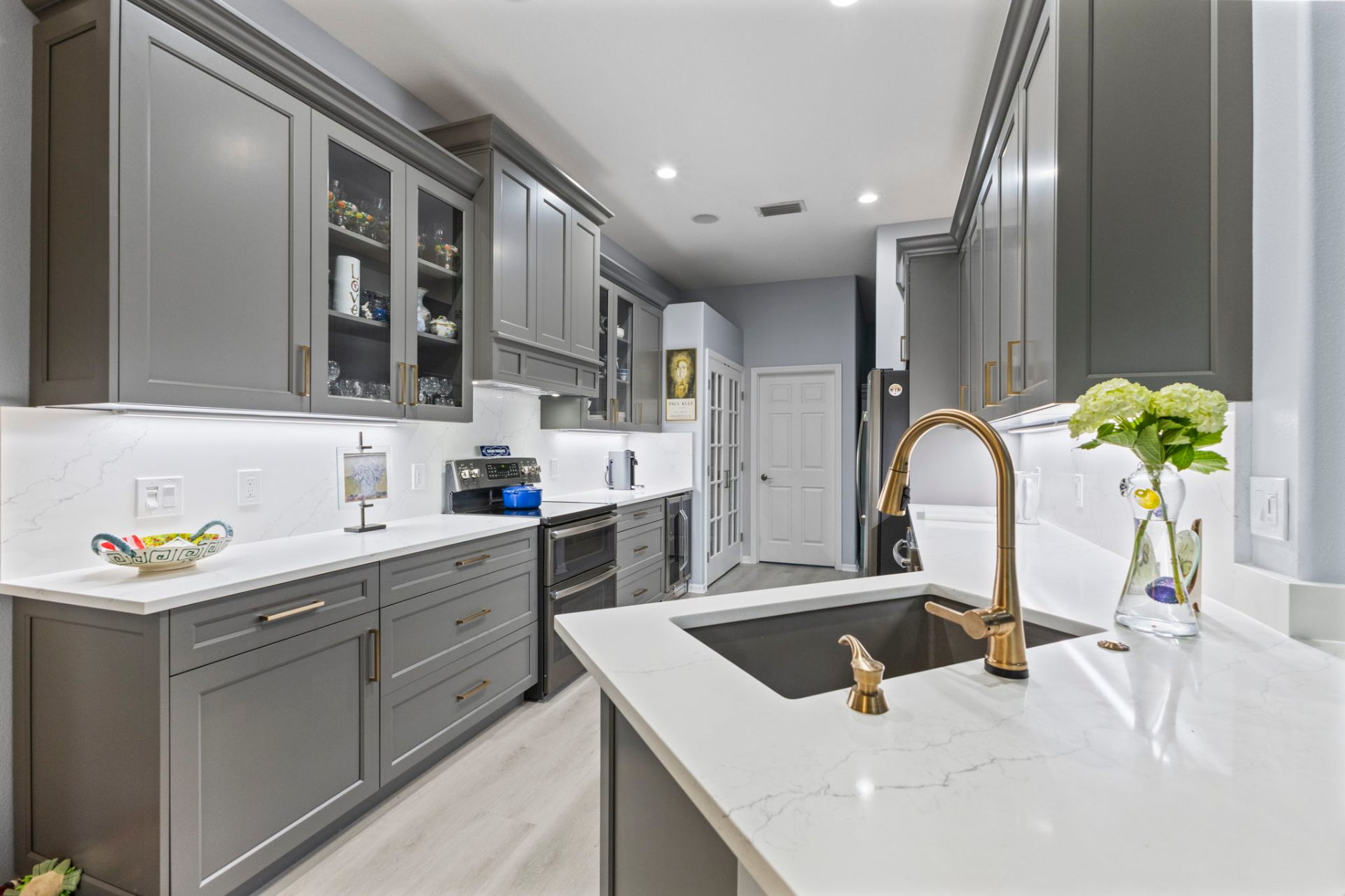 Grey painted kitchen with brass hardware and white quartz island — The Lewis Project, River Club